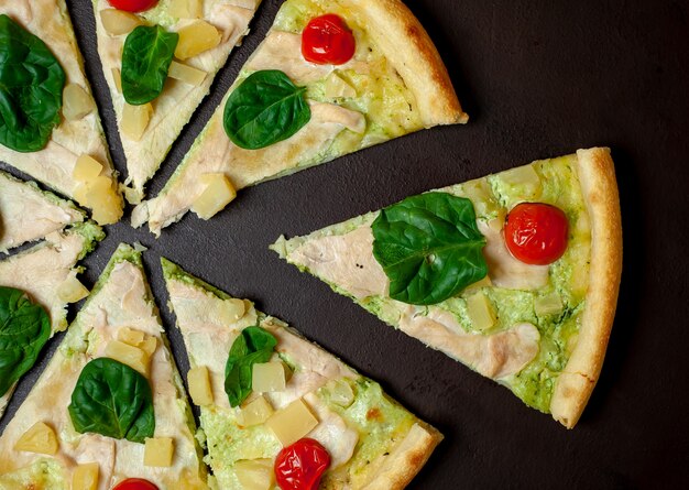 köstliche Pizza mit Ananas, Tomaten, Mozzarella-Käse, Hühnerfilet auf einem Steinhintergrund