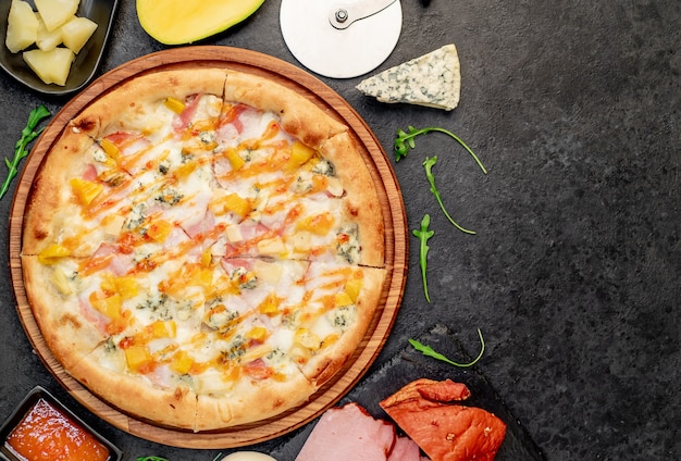 köstliche Pizza mit Schinken-Käse-Ananas-Mango auf einem Steinhintergrund mit Kopienraum für Ihren Te