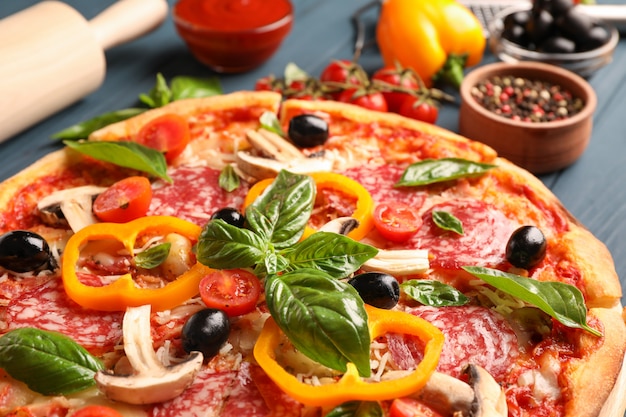 Köstliche Pizza und Zutaten auf hölzernem Hintergrund