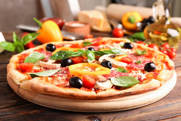 Köstliche Pizza und Zutaten auf hölzernem Hintergrund