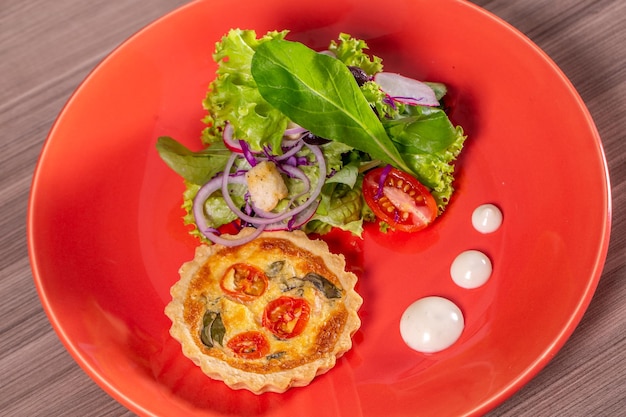 Köstliche Quiche mit Salat serviert in buntem Geschirr