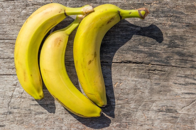 Köstliche reife gelbe Bananen auf rustikalem Holztisch. Ansicht von oben