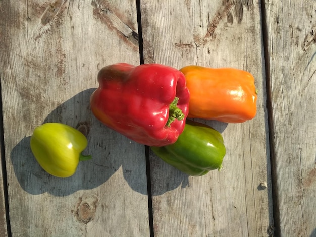 Köstliche reife saftige rote orange grüne Paprika auf einem alten Holztisch