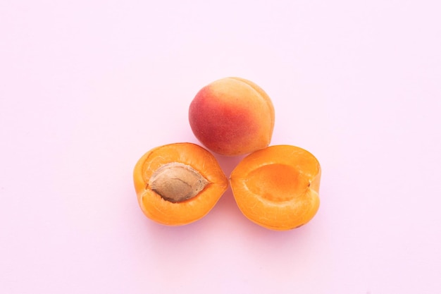 Köstliche reife süße Aprikosen auf rosa Hintergrund flach gelegt