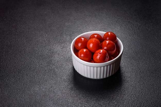 Köstliche rote Kirschtomaten aus der Dose in weißer Piala auf einem dunklen Betontisch