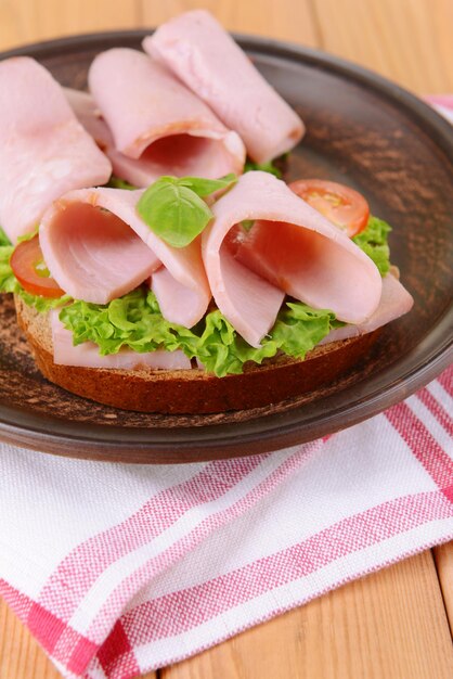 Köstliche Sandwiches mit Salat und Schinken auf dem Teller auf dem Tisch in der Nähe