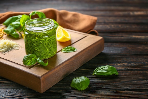 Köstliche Sauce im Glas mit Zutaten auf Holzbrett