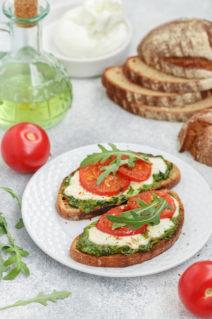 Foto köstliche schwarze roggenbrot-sandwichesxamit pesto buratta-käse oder mozzarella-tomaten und frischem rucola brunch mediterrane küche selektiver fokus