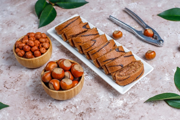 Köstliche süße Schokoladenkuchenrolle mit Haselnusscreme und Haselnüssen, Draufsicht