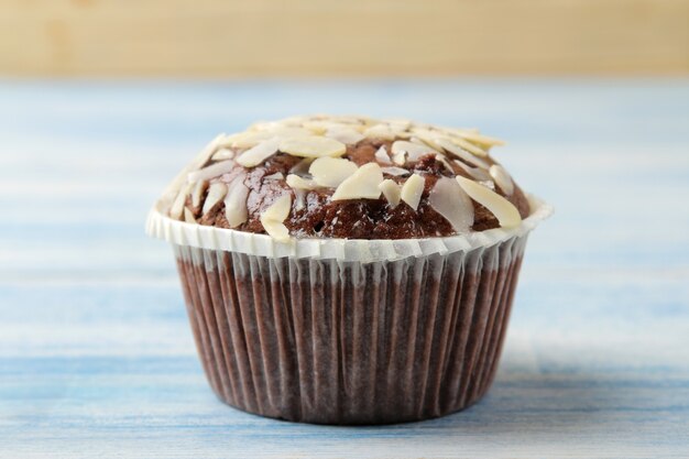 Köstliche, süße Schokoladenmuffins mit Mandelblüten auf einem blauen Holztisch.