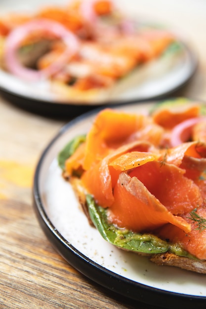 Köstliche Toasts mit geräuchertem Lachs, Avocado und Basilikumblättern