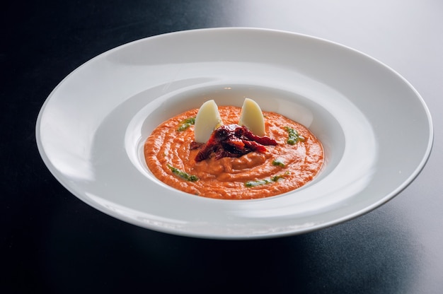 Köstliche Tomatensuppe mit getrockneten Tomaten und Wachteleiern, serviert in einem tiefen Teller