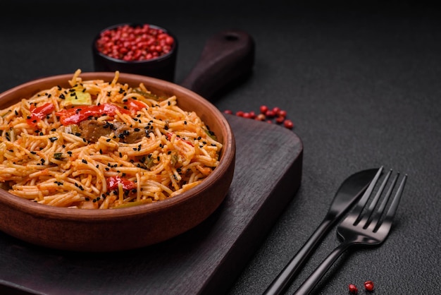 Köstliche Udon-Nudeln mit Fleisch oder Meeresfrüchten, Gemüse, Salz und Gewürzen auf einem dunklen Beton-Hintergrund