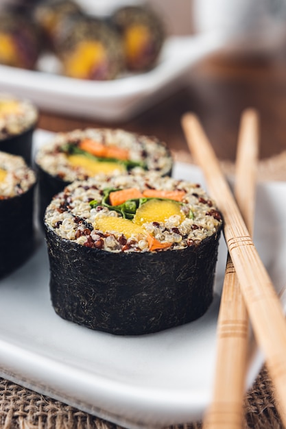 Foto köstliche vegane sushi-rolle mit holzstäbchen
