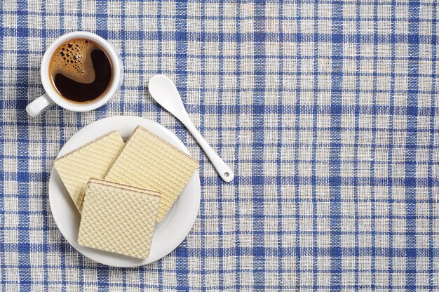 Köstliche Waffeln mit Schokolade und heißem Kaffee auf verdeckter blauer Tischdecke des Tisches, Ansicht von oben