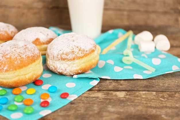 Köstliche zuckerhaltige Donuts mit blauer Serviette auf Holzhintergrund