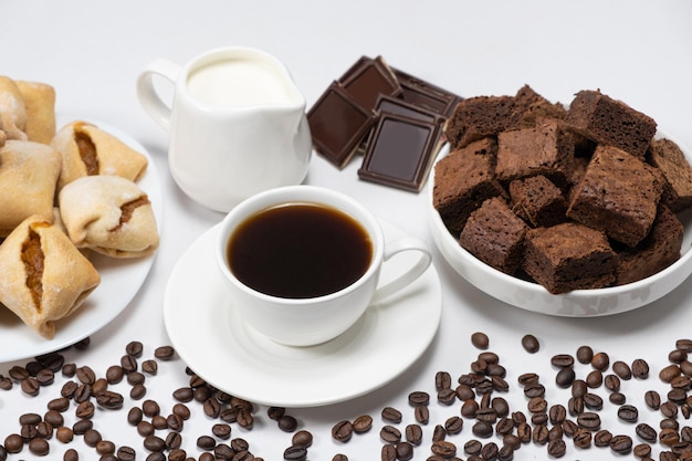 Köstlicher aromatischer Frühstückskaffee in einer Tasse Milchkännchen Schokolade und Kuchenwürfel