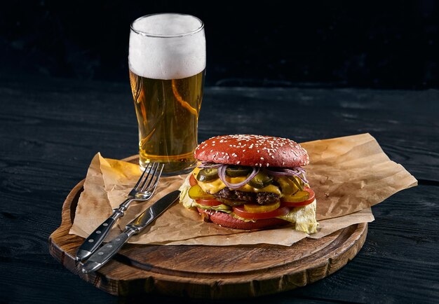 Köstlicher Burger mit Bier und Pommes Frites auf einem hölzernen rustikalen Tisch Gamberger mit Salom Zwiebeln und