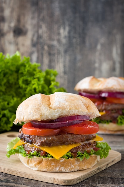 Köstlicher Burger mit Cheddar-Käse, Tomate, Salat und Zwiebel. Schwarz und dunkel