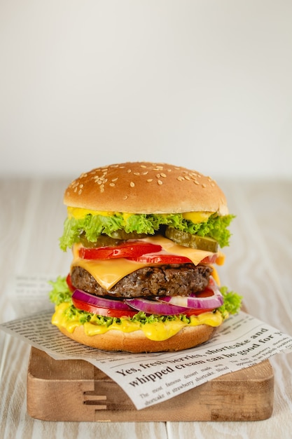 Köstlicher Burger mit Fleisch, geschmolzenem Käse, tropfender Soße und Gemüse auf weißem rustikalem Hintergrund. Frisch zubereiteter leckerer Hamburger, Nahaufnahme