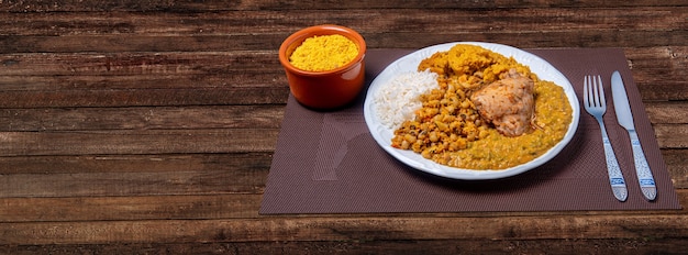 Köstlicher Caruru. Traditionelles afro-brasilianisches Gericht aus Okra und getrockneten Garnelen, begleitet von Vatapa, Bohnen, Reis, Hühnchen und Farofa. Auf einem Holztisch.