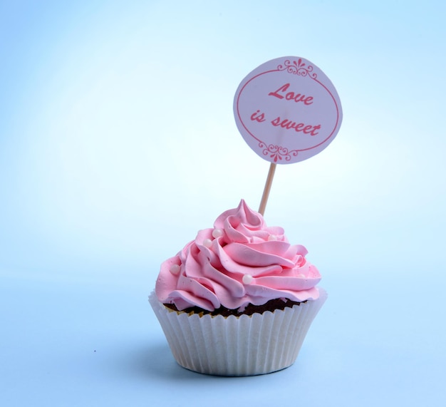 Foto köstlicher cupcake mit inschrift auf dem tisch auf blauem hintergrund