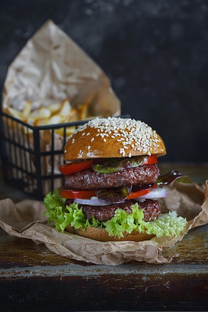 Köstlicher Doppelburger mit Pommes Frites auf dunklem Hintergrund, stimmungsvolles Restaurant, Food-Fotografie