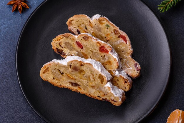 Foto köstlicher festlicher neujahrskuchen mit kandierten früchten, marzipan und nüssen auf dunklem betonhintergrund