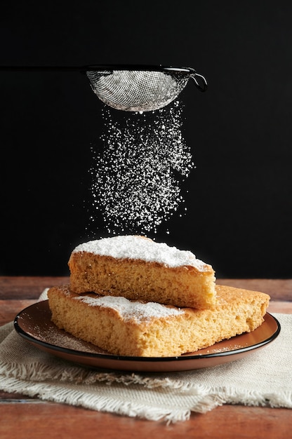 Köstlicher frisch gebackener Biskuitkuchen mit Puderzucker bestreuen