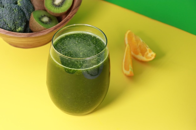 Köstlicher frischer grüner Kiwi-Smoothie mit Orangensaft auf gelbem Hintergrund, Kopierraum