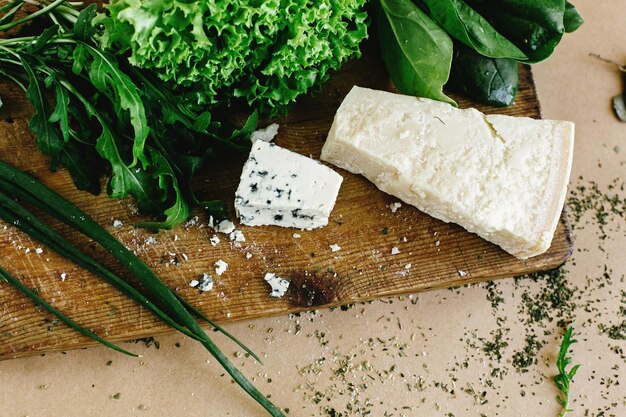 Foto köstlicher frischer salat arugula spinat und parmesan und gorgonzola-käse auf draufsicht aus holzkochbrett