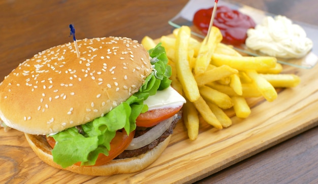 Köstlicher gegrillter Hamburger mit Kartoffelchips auf Holzbrett