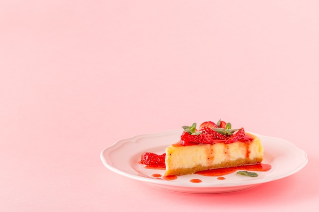 Köstlicher hausgemachter Käsekuchen mit Erdbeeren auf rosa.