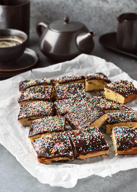 Köstlicher hausgemachter Kuchen mit dunkler Schokoladenglasur und bunten Zuckerstreuseln auf Backpapier