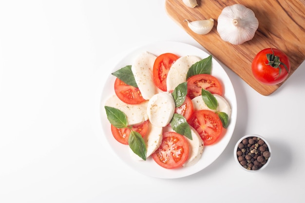 Köstlicher italienischer Caprese-Salat mit in Scheiben geschnittenen Mozzarella-Tomaten-Basilikum-Pesto und Knoblauch im Hintergrund