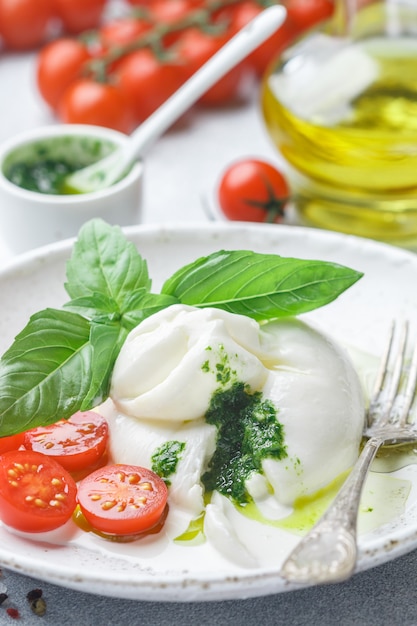 Köstlicher italienischer frischer Burrata mit Kirschtomaten, Basilikum Pesto und Olivenöl