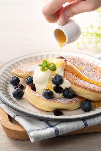 Köstlicher japanischer Auflaufpfannkuchen mit Heidelbeerpreiselbeere und -honig auf Holztischhintergrund Beschneidungspfad eingeschlossen