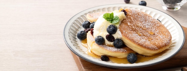 Köstlicher japanischer Auflaufpfannkuchen mit Heidelbeerpreiselbeere und -honig auf Holztischhintergrund Beschneidungspfad eingeschlossen