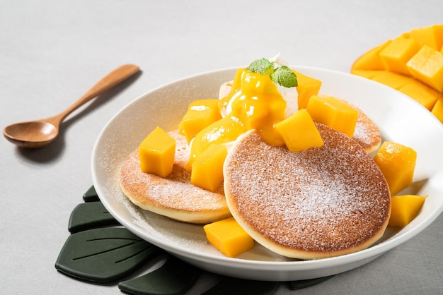 Köstlicher japanischer Auflaufpfannkuchen mit Mangowürfeln und Marmelade auf grauem Tischhintergrund