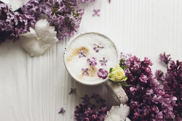 Köstlicher Kaffee mit Fliederblättern und Fliederzweig auf rustikalem weißem Holz flach lag Fröhlicher Muttertag