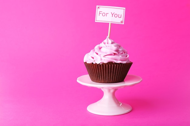 Foto köstlicher kleiner kuchen mit aufschrift auf rosa hintergrund