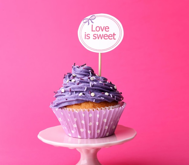 Foto köstlicher kleiner kuchen mit aufschrift auf rosa hintergrund