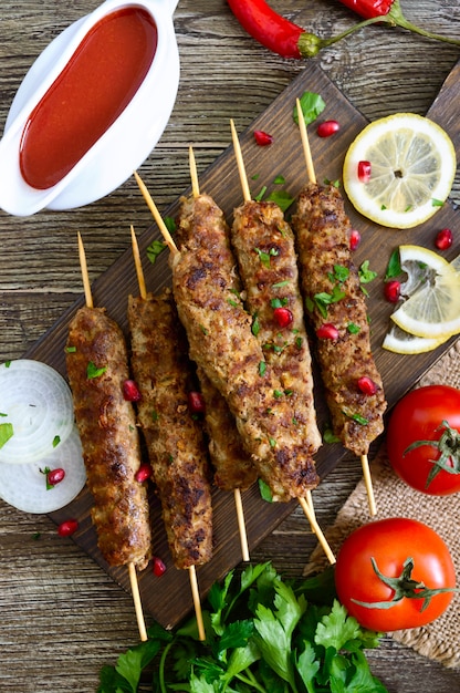 Köstlicher Lula-Kebab auf einem Holztisch. Gehacktes Fleisch auf Holzspießen, gegrillt.