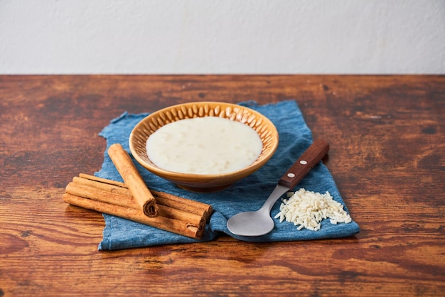 Köstlicher Milchreis oder Arroz con Leche mit Zimt in Schüssel auf Holztisch