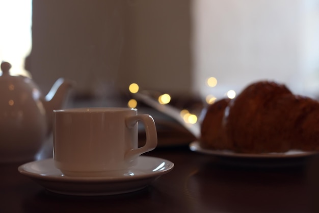 Köstlicher Morgenkaffee und Croissant werden zum Frühstück auf einem Holztisch serviert
