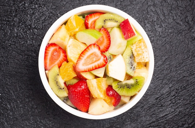 Köstlicher Obstsalat auf dem schwarzen Tisch