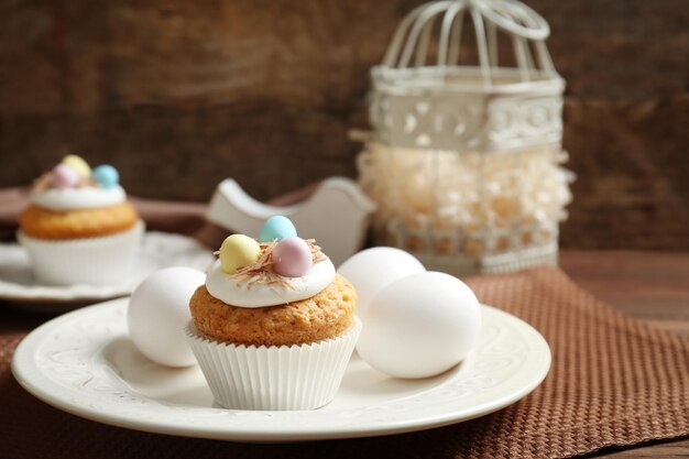 Köstlicher Ostern-kleiner Kuchen auf weißer Platte gegen hölzernen Hintergrund Beschneidungspfad eingeschlossen