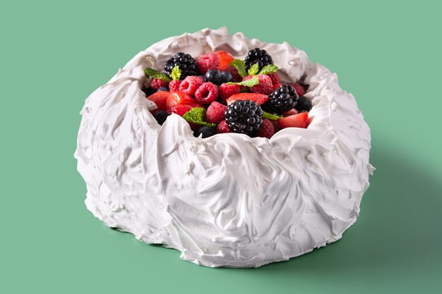 Köstlicher Pavlova-Kuchen mit Baiser und frischen Beeren auf grünem Hintergrund