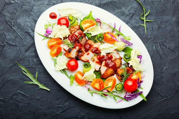 Köstlicher Salat mit Tomaten, Gurken, Salat und Fleischsteak. Gesunder Salat auf weißem Teller