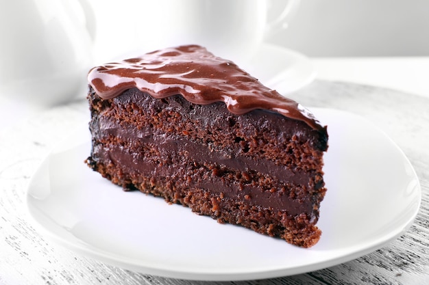 Köstlicher Schokoladenkuchen auf Teller auf Tisch auf hellem Hintergrund
